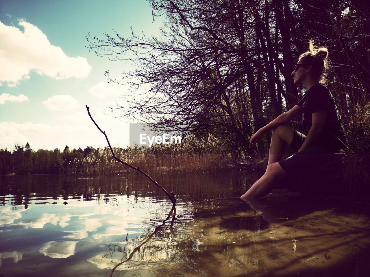 Side view of woman in lake against sky