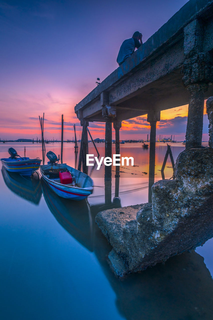 BOATS MOORED IN SEA AGAINST SKY DURING SUNSET