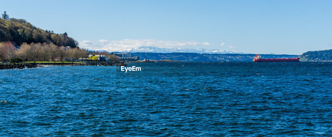 A view of the waterfront in ruston, washington with the olympic mountains in the distance.