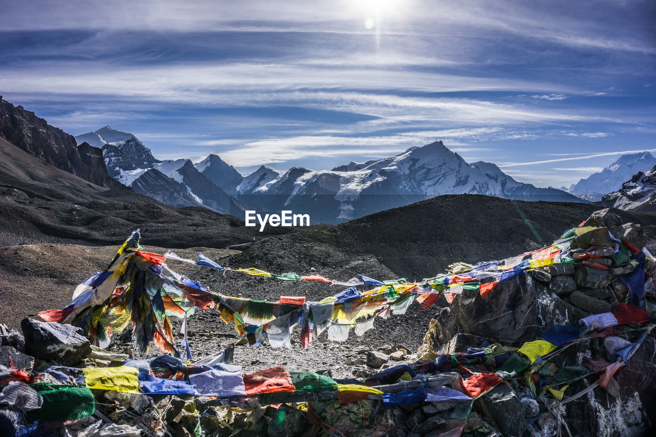 MULTI COLORED FLAGS HANGING ON MOUNTAIN AGAINST SKY