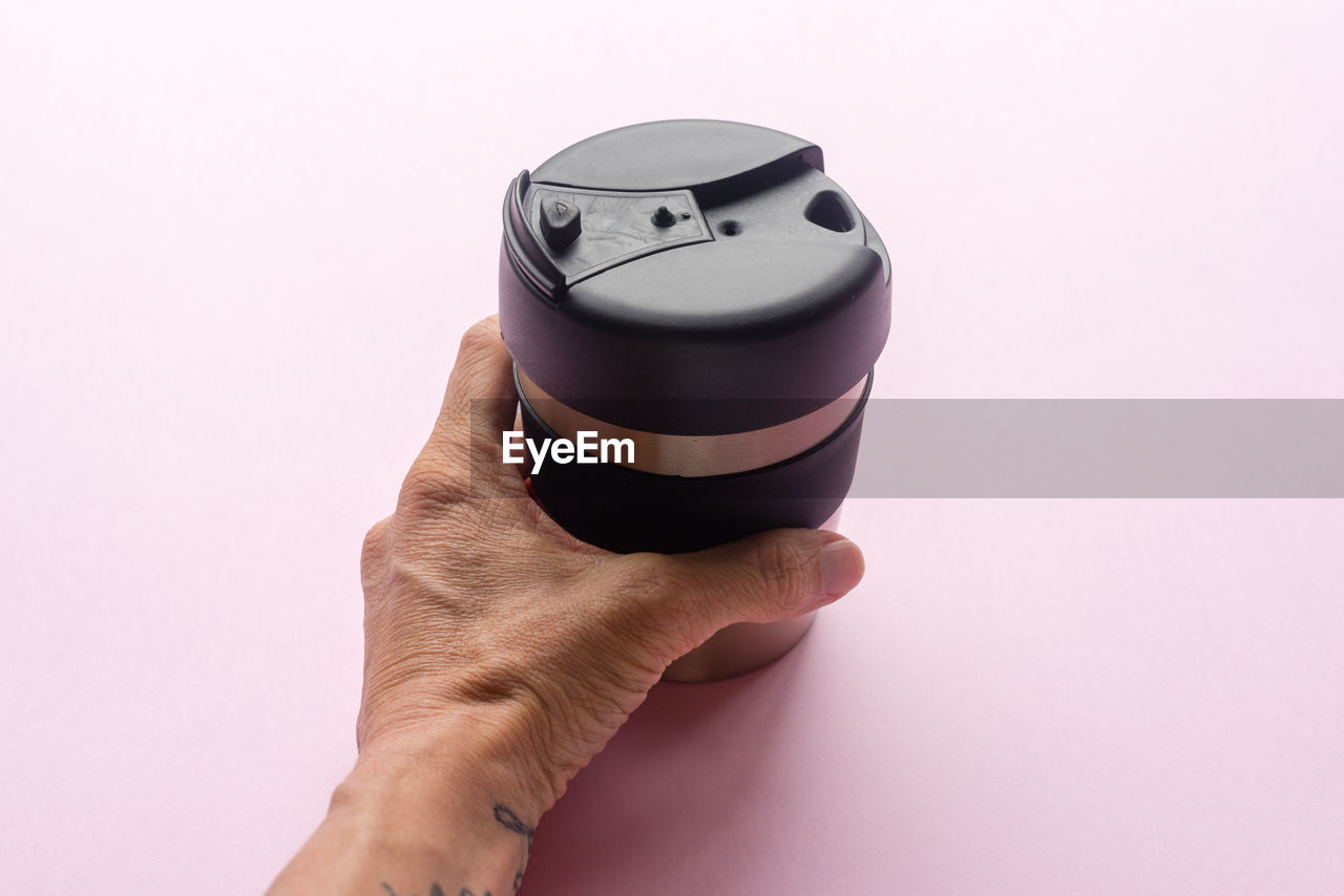 Cropped hand of woman holding camera lens on table