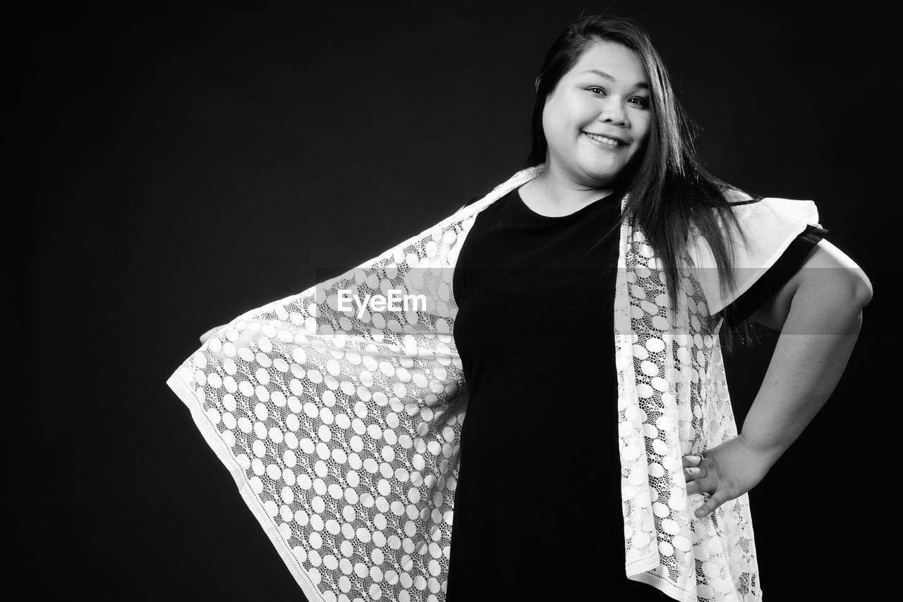 Portrait of a smiling young woman against black background