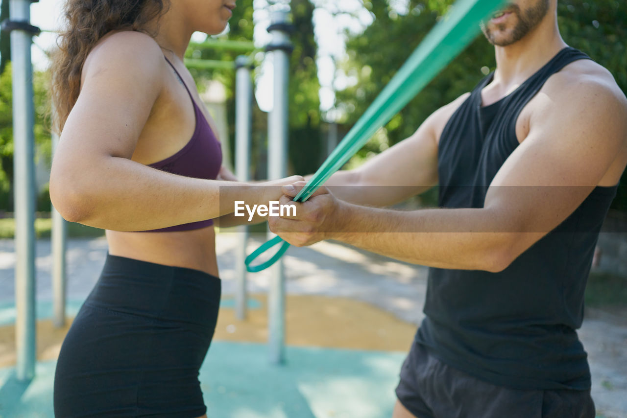 Detail of a man and woman practicing calisthenics with an elastic band