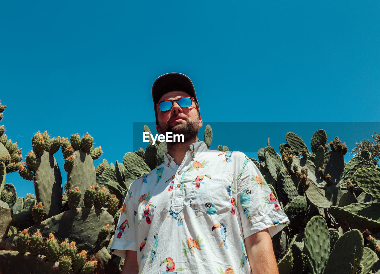 Low angle view of man standing against clear blue sky