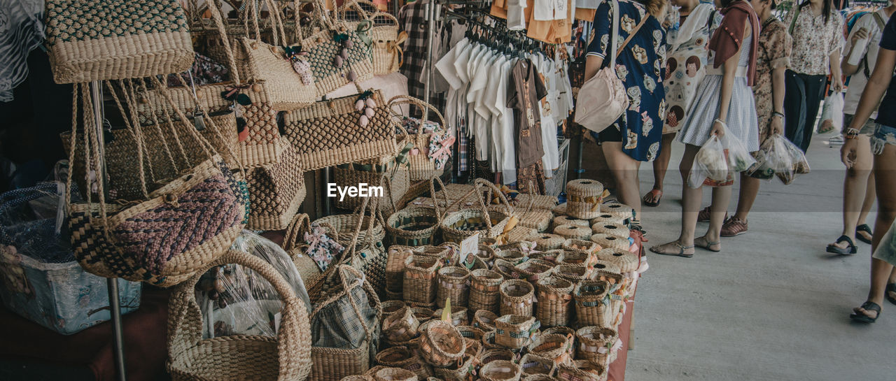 Low section of women standing by woven baskets and handbags at market