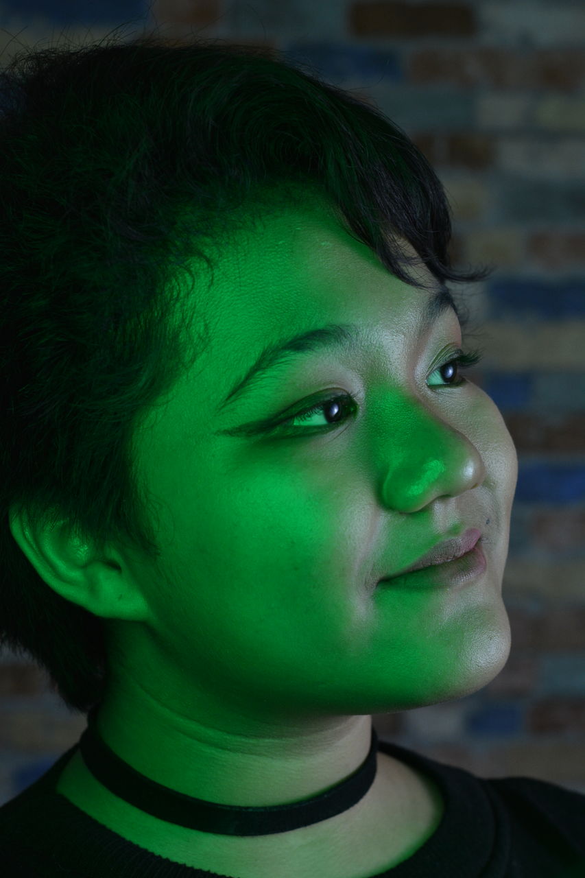 Low lit portrait of a young girl with colored light as accent