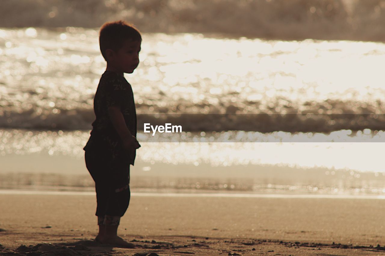 BOY STANDING ON BEACH
