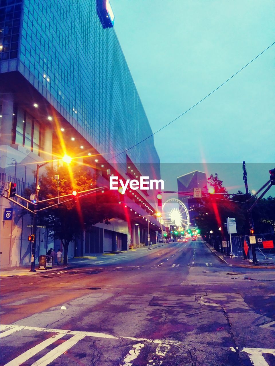 ILLUMINATED CITY STREET AGAINST SKY AT NIGHT