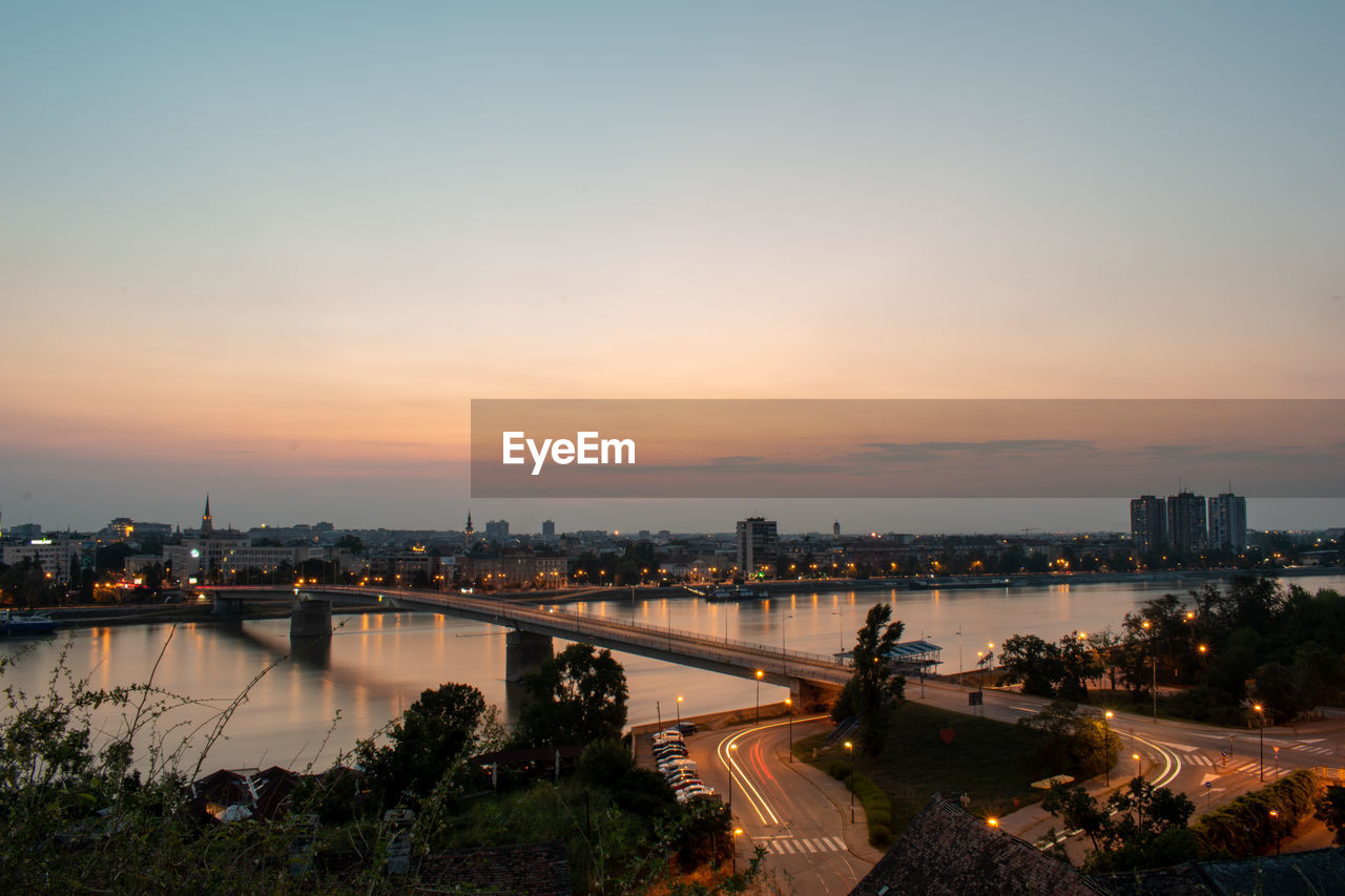 architecture, city, built structure, sky, building exterior, dusk, sunset, water, evening, horizon, nature, cityscape, transportation, travel destinations, building, illuminated, night, river, skyline, reflection, landscape, bridge, urban skyline, travel, high angle view, no people, outdoors, twilight, city life, street, tourism, coast, cloud, urban area, mode of transportation