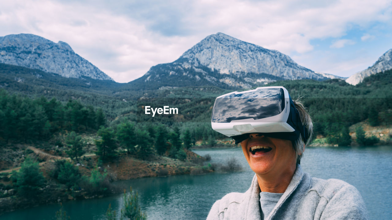 Woman wearing virtual reality simulator against mountains and sky