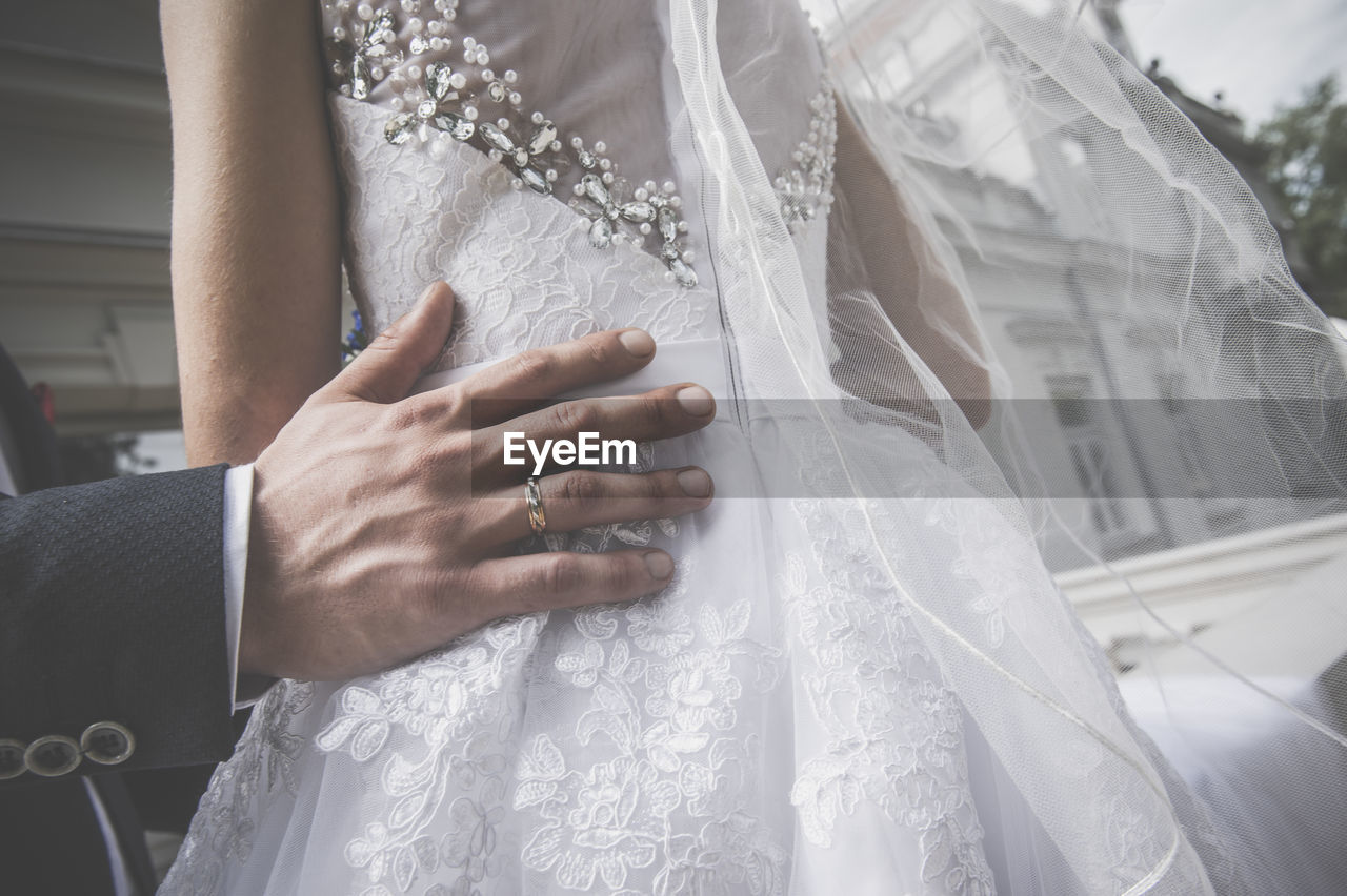 Cropped hand of bridegroom touching bride