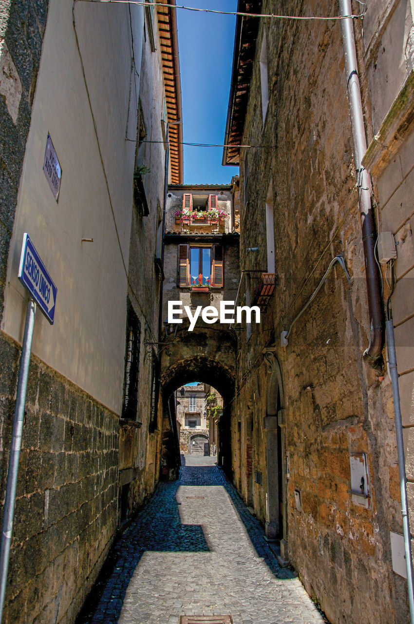 Narrow alleyway with old buildings and traffic sign at the town of orvieto, italy.