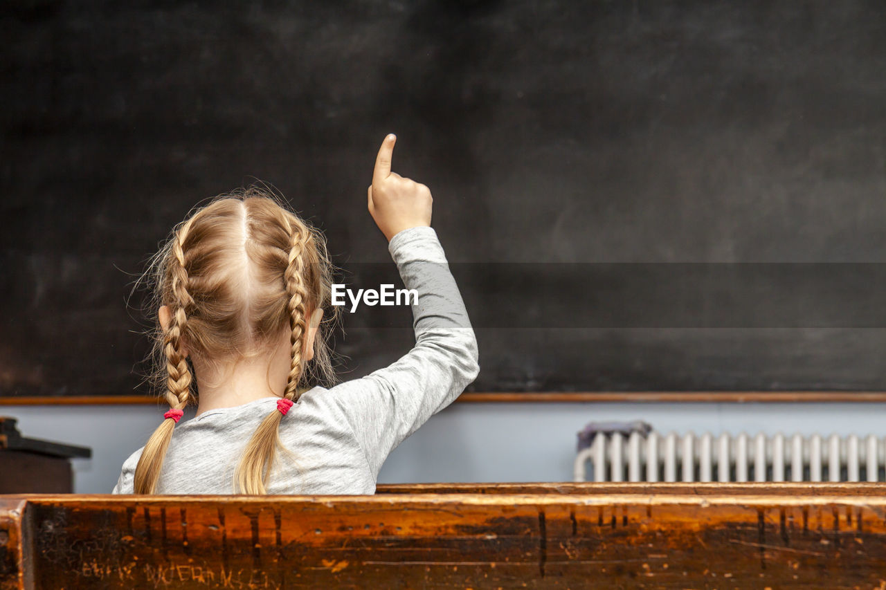 Rear view of girl sitting in classroom