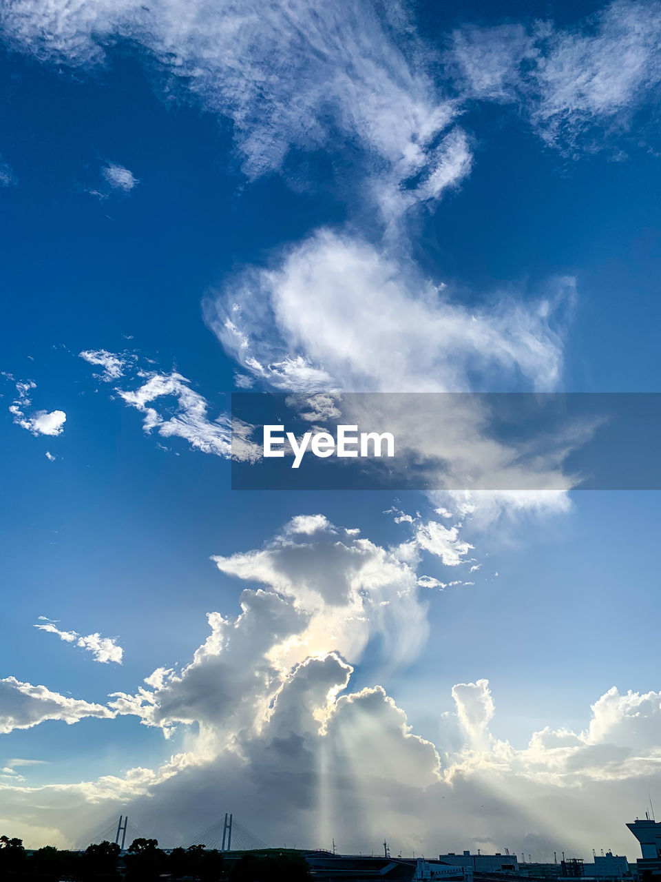LOW ANGLE VIEW OF SUN STREAMING THROUGH CLOUDS IN SKY