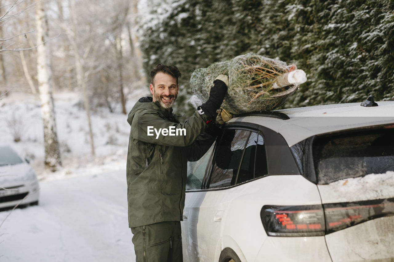 Man putting christmas tree on car roof