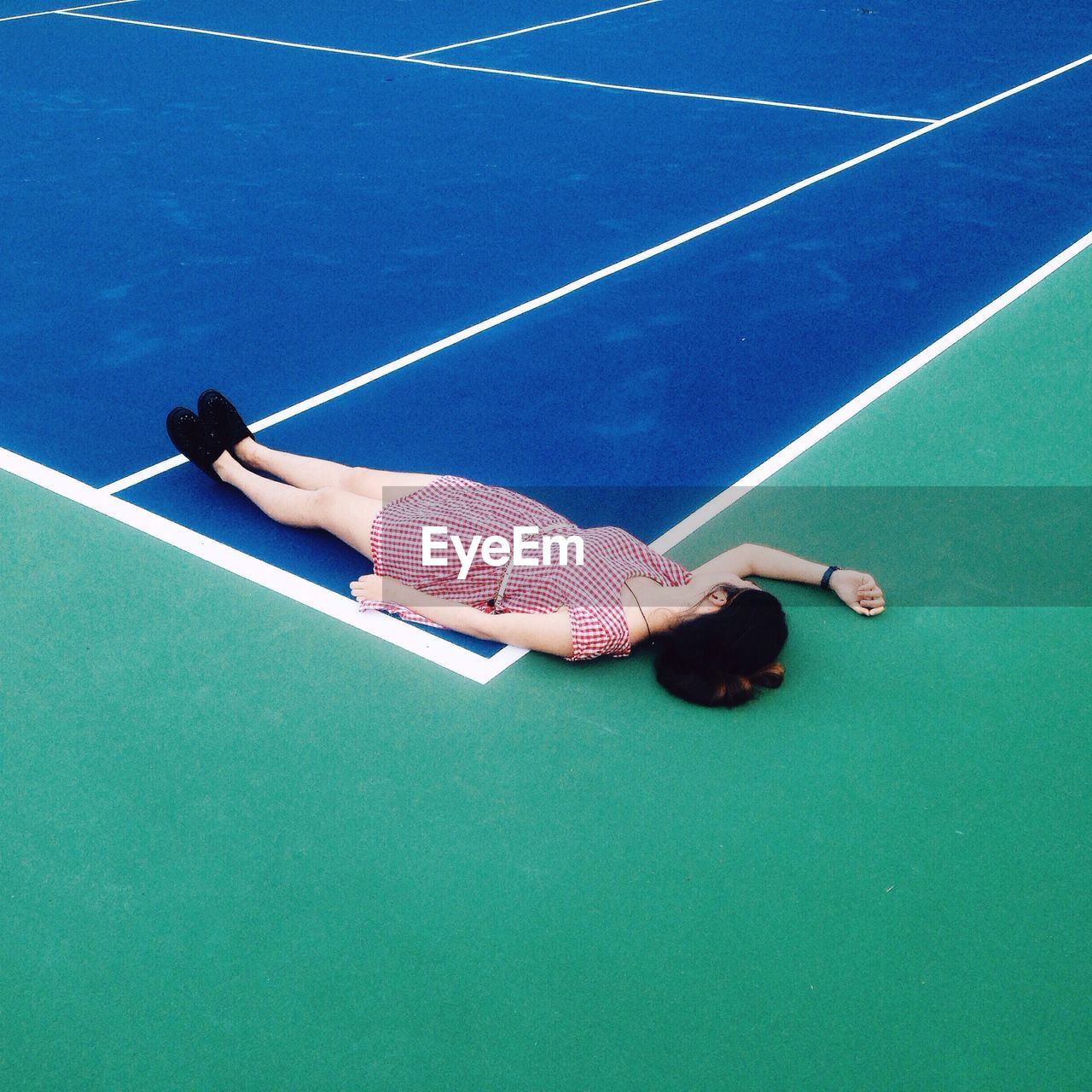 High angle view of woman sleeping at tennis field