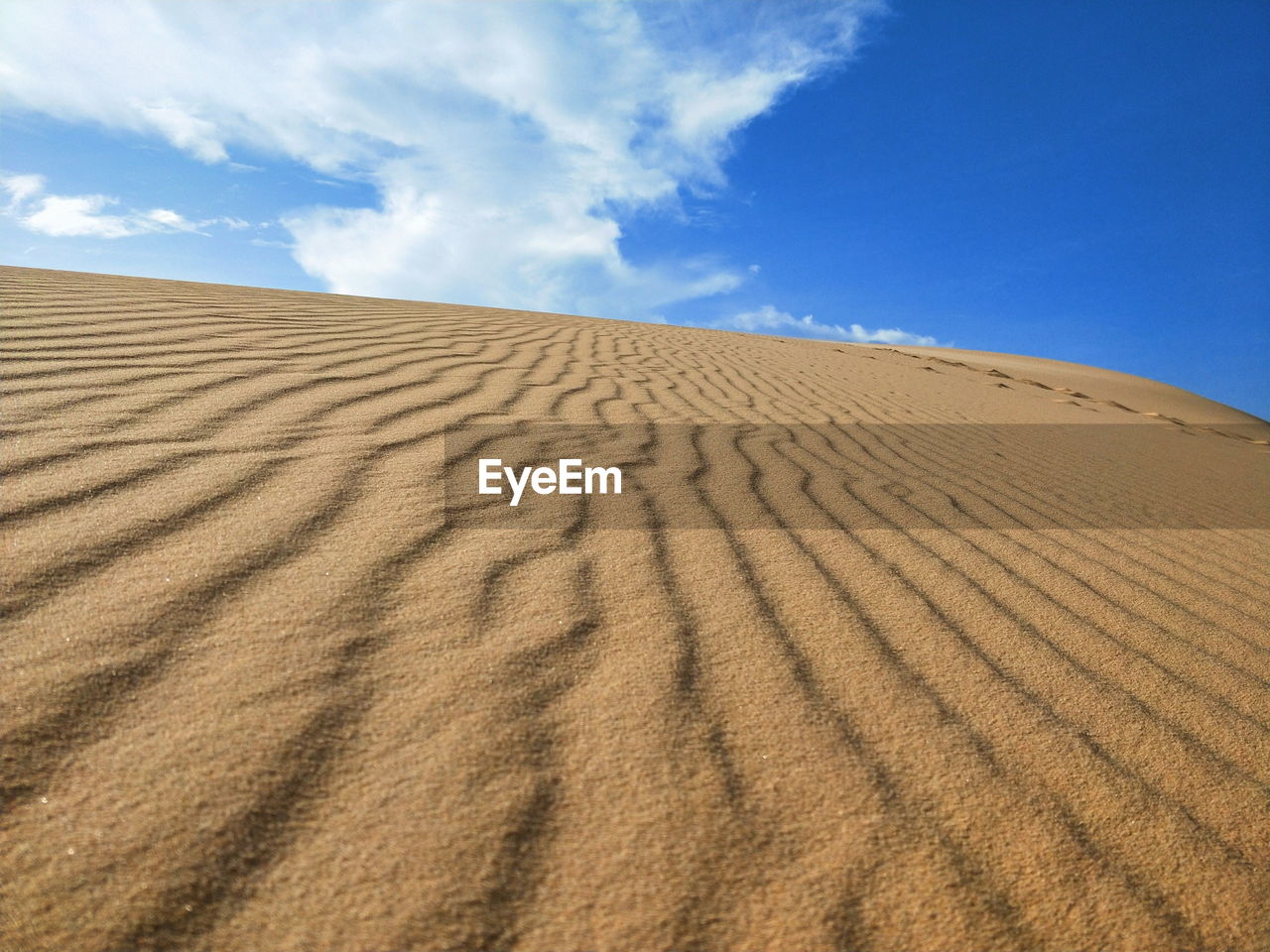 Sand dune in desert against blue sky