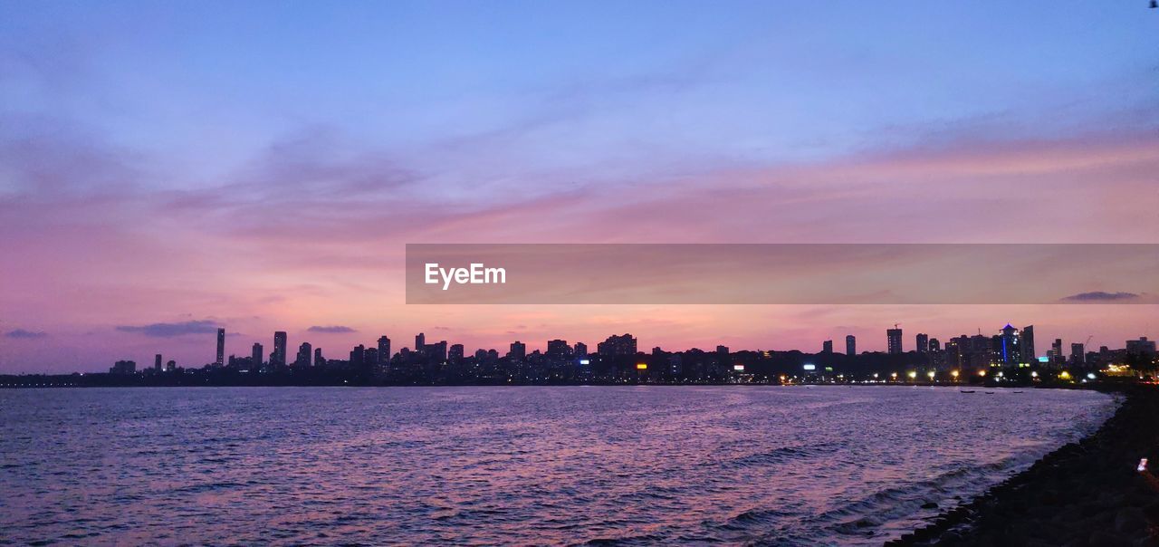 SEA AND BUILDINGS AGAINST SKY DURING SUNSET