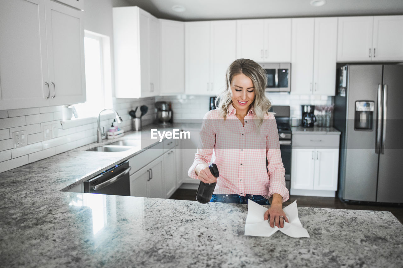 Woman cleaning kitchen counter at home