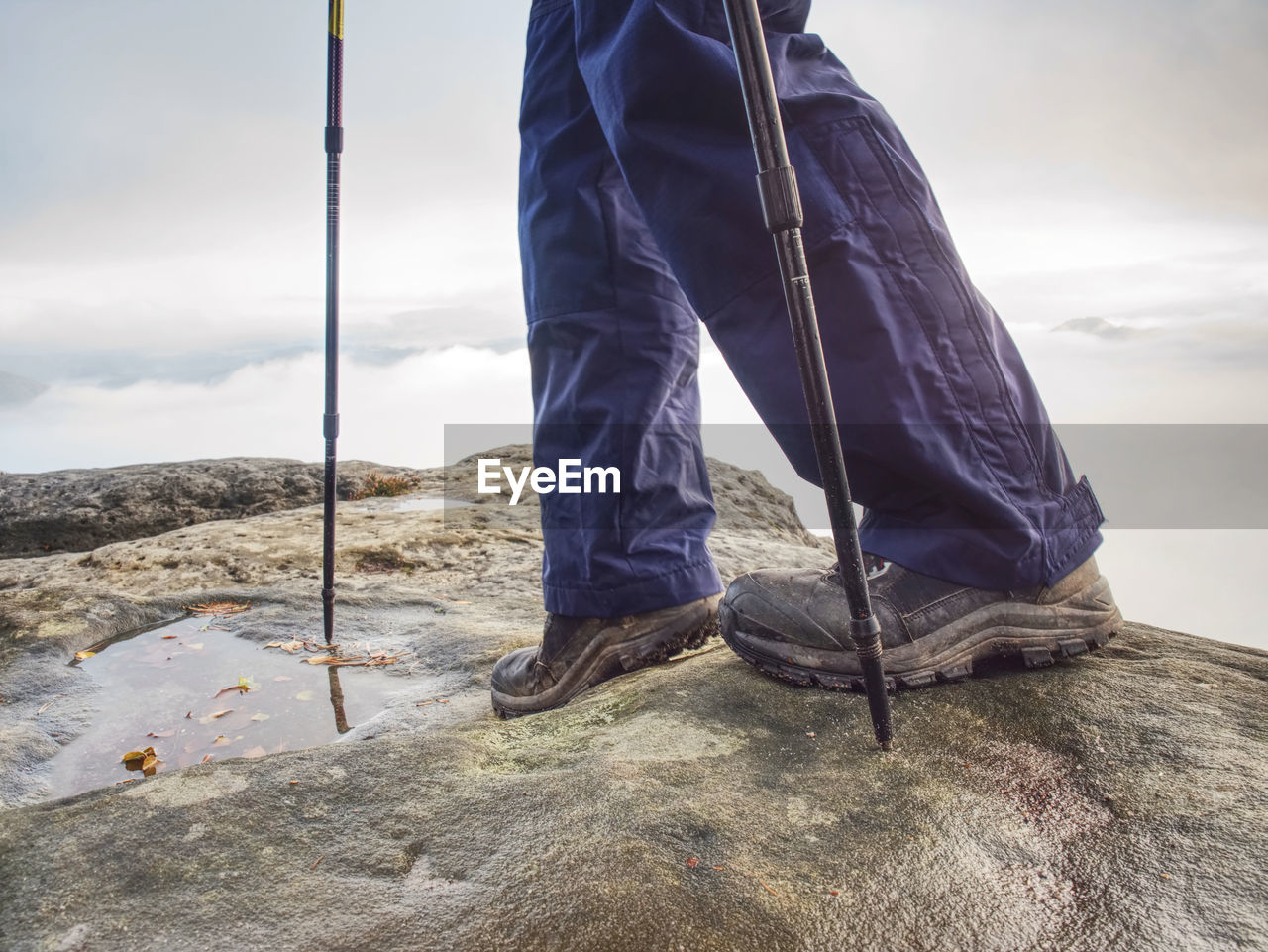 Man hiker legs stand on mountain peak rock. slippery journey at the edge