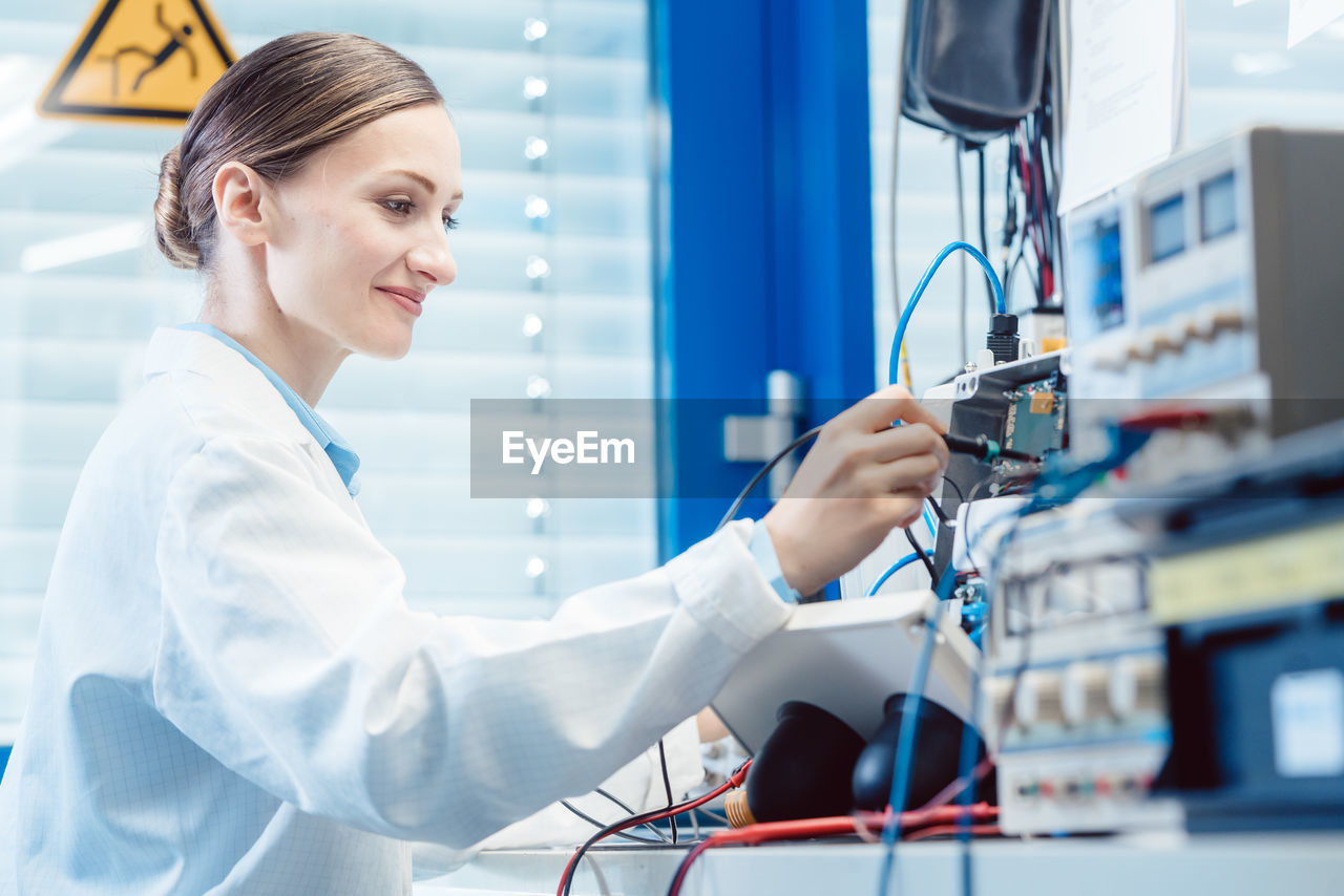 Female technician repairing equipment at workplace