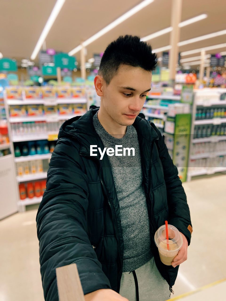 Young man looking away while standing at store