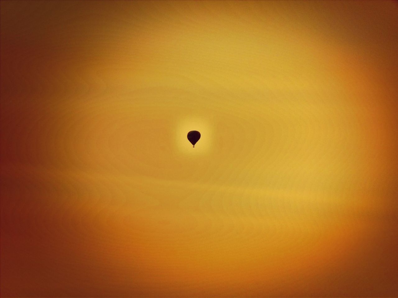 Low angle view of silhouette hot air balloon in orange sky