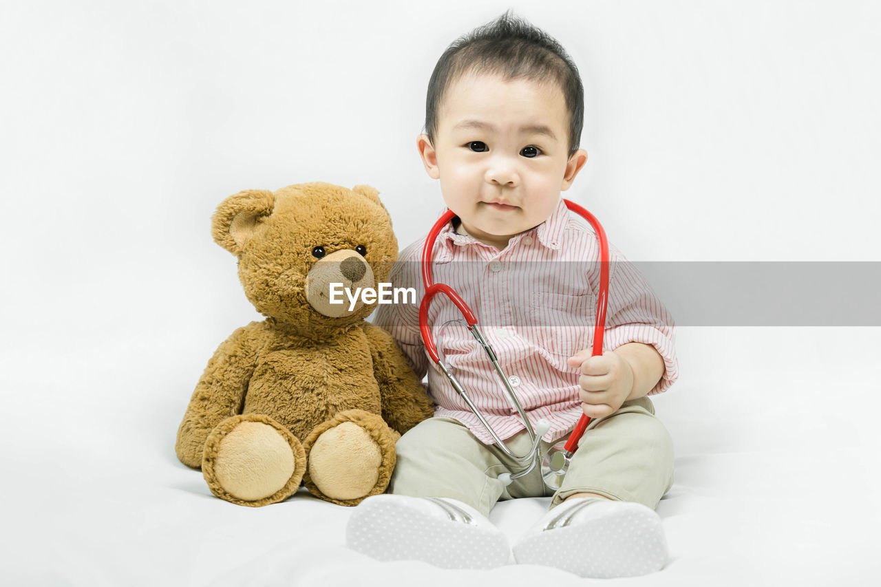 childhood, child, toy, one person, teddy bear, cute, baby, stuffed toy, indoors, sitting, white background, innocence, person, happiness, studio shot, smiling, full length, emotion, portrait, front view, men, toddler, cheerful, cut out, animal representation, fun, looking at camera, positive emotion, lifestyles, human face
