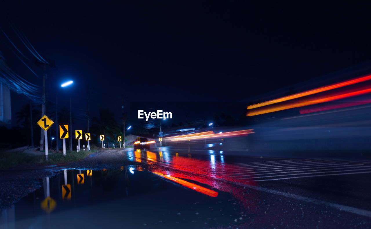 ILLUMINATED LIGHT TRAILS ON ROAD AT NIGHT