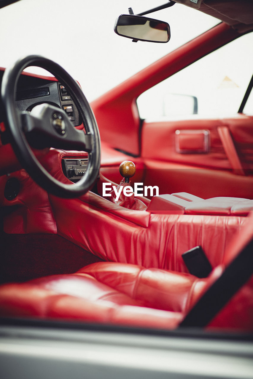 CLOSE-UP OF RED VINTAGE CAR ON BUS