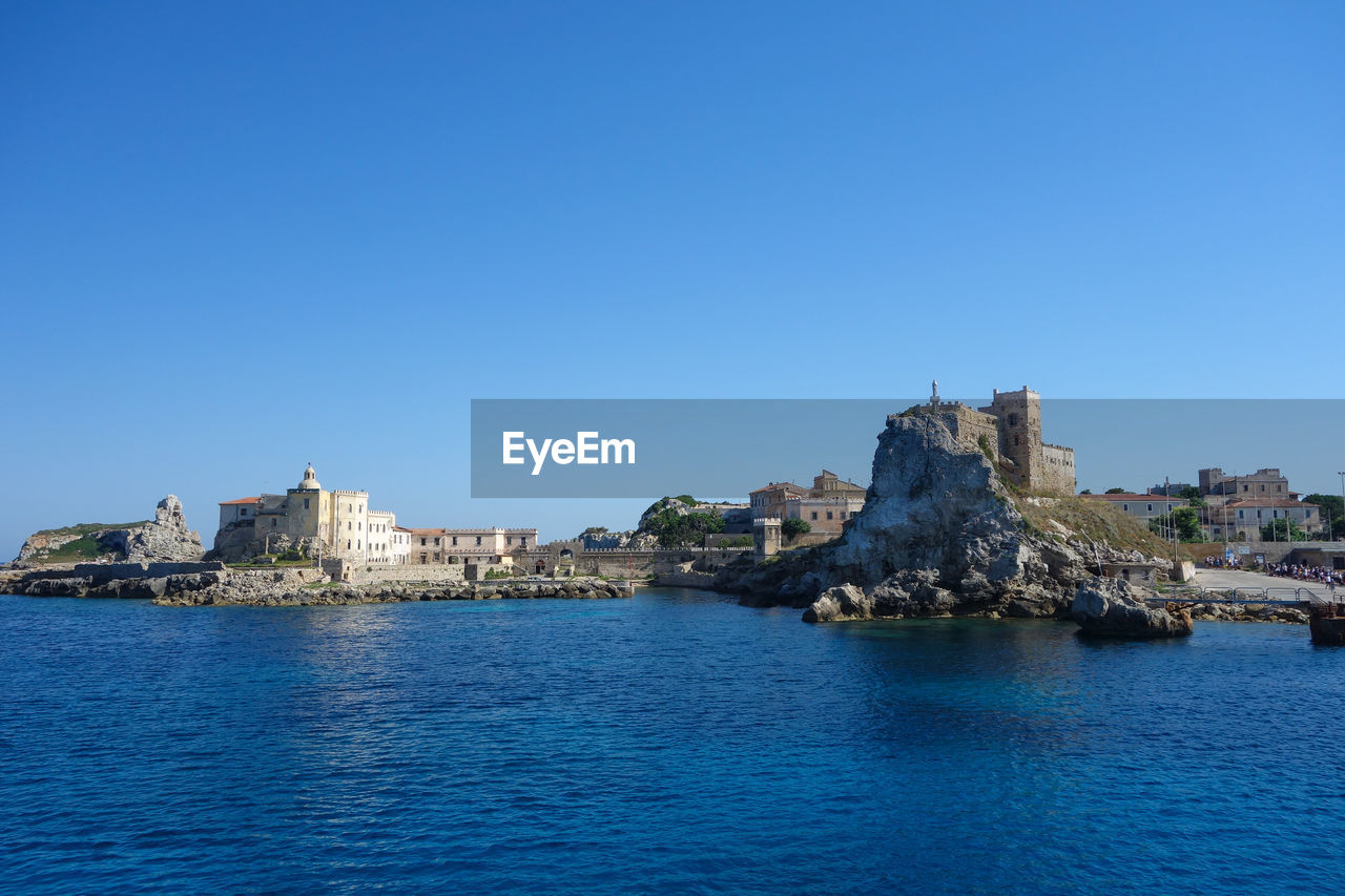 scenic view of sea by buildings against clear blue sky