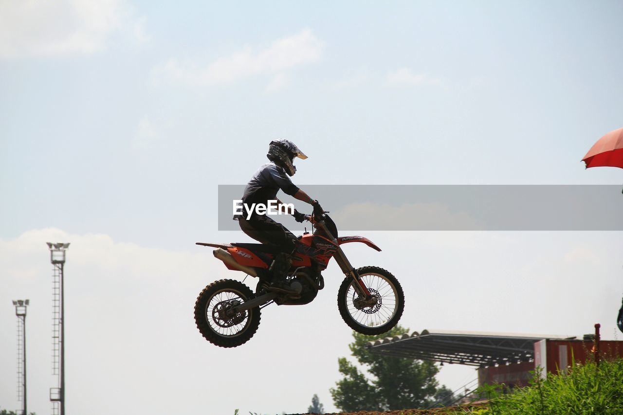 motorcycle, motocross, stunt, real people, extreme sports, mid-air, riding, risk, crash helmet, jumping, men, helmet, day, one person, outdoors, adventure, sports race, biker, speed, sky, skill, motorsport, mode of transport, full length, motorcycle racing, transportation, headwear, performance, sports helmet, lifestyles, competition, stunt person, sports clothing, competitive sport, sports track, people