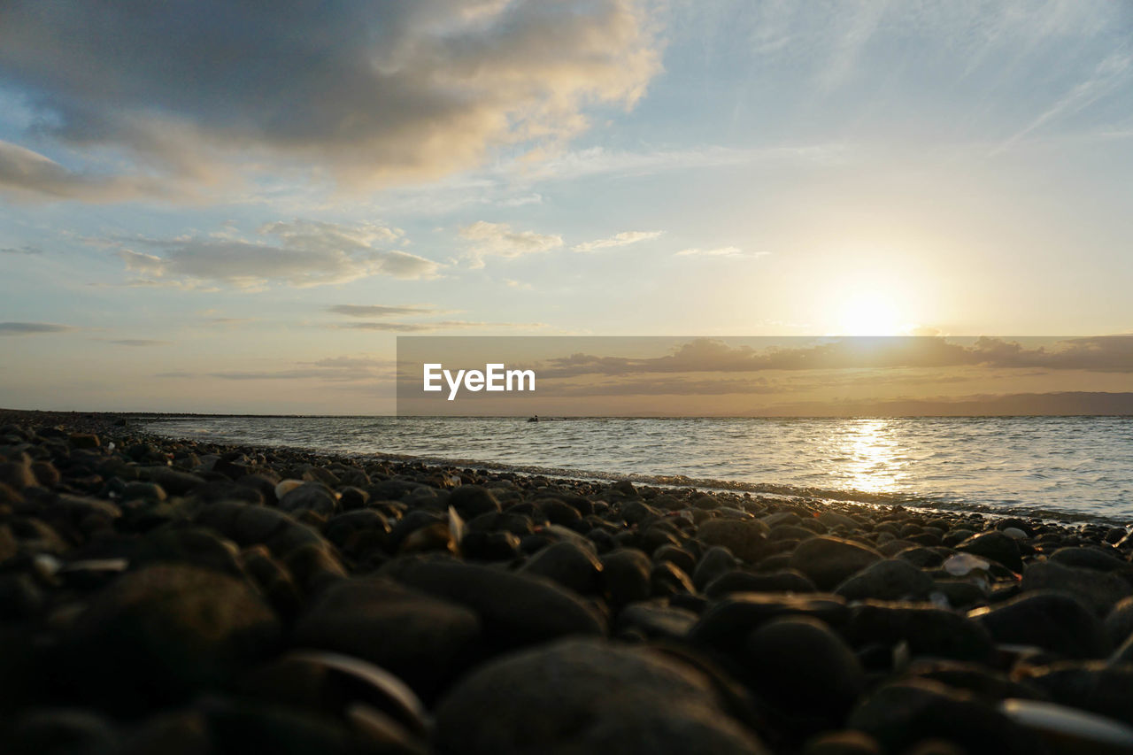 Rocks on beach against sky during sunset