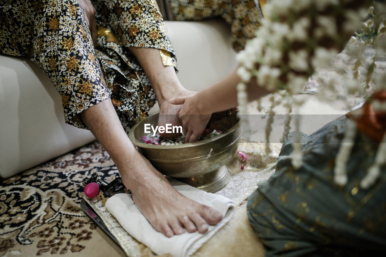 Midsection of bride washing woman legs on floor