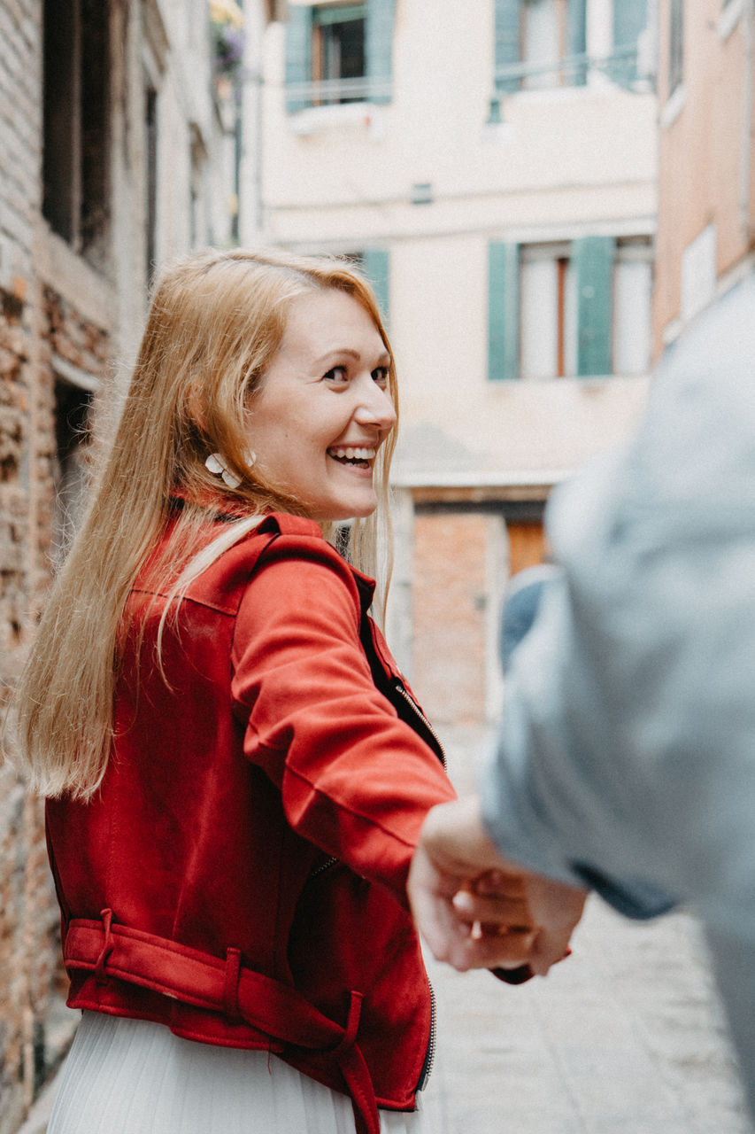 Couple holding hands while standing against buildings