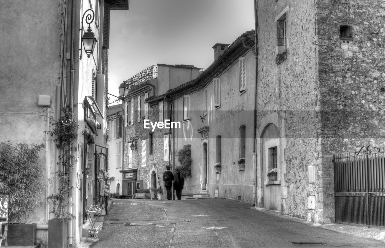 Rear view of people walking on road amidst buildings