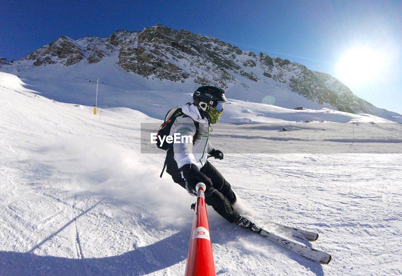 MAN SKIING ON SNOWCAPPED MOUNTAINS AGAINST SKY