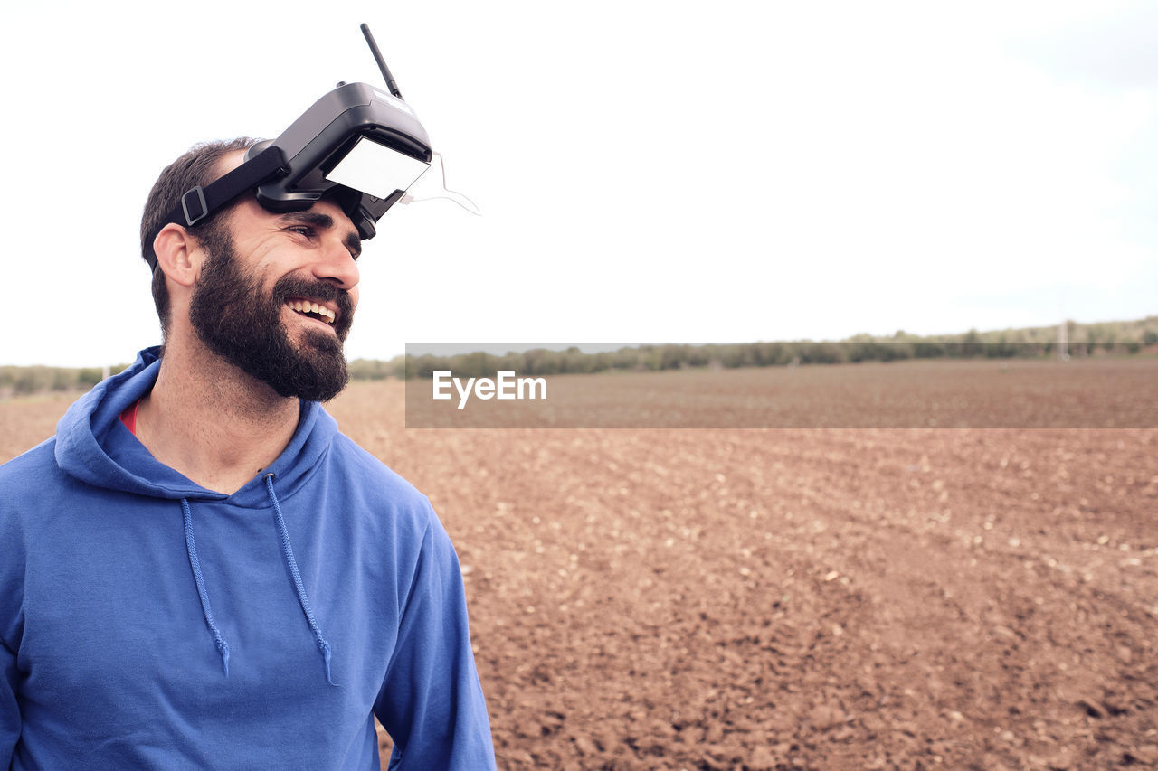 Man smiles in the field with his 3d glasses after blowing up his drone