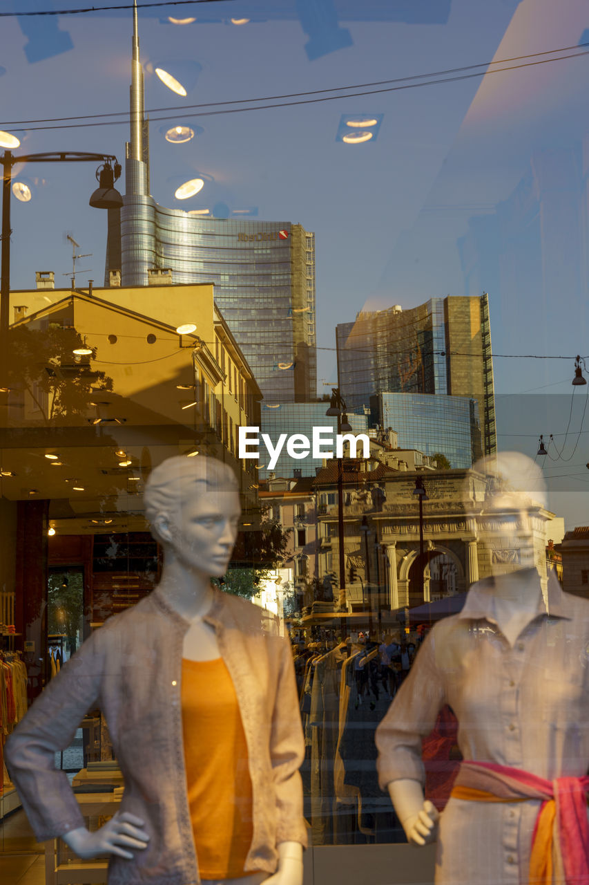 REAR VIEW OF MAN AND WOMAN STANDING ON STREET AT CITY