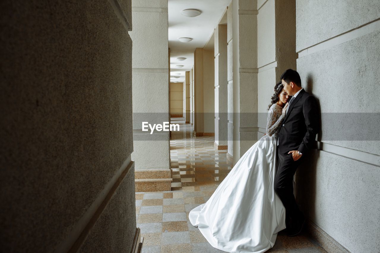 Wedding couple standing in corridor against wall