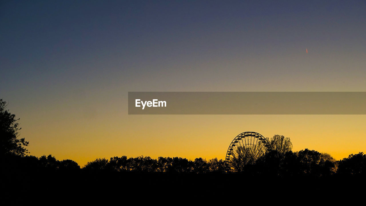 SILHOUETTE OF FERRIS WHEEL AGAINST CLEAR SKY
