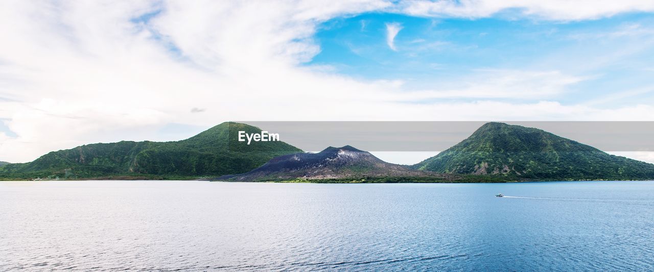 Scenic view of sea by mountains against sky