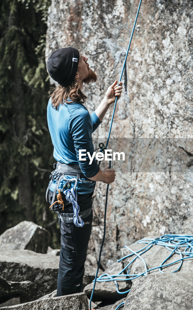 Rear view of man standing in forest with rope