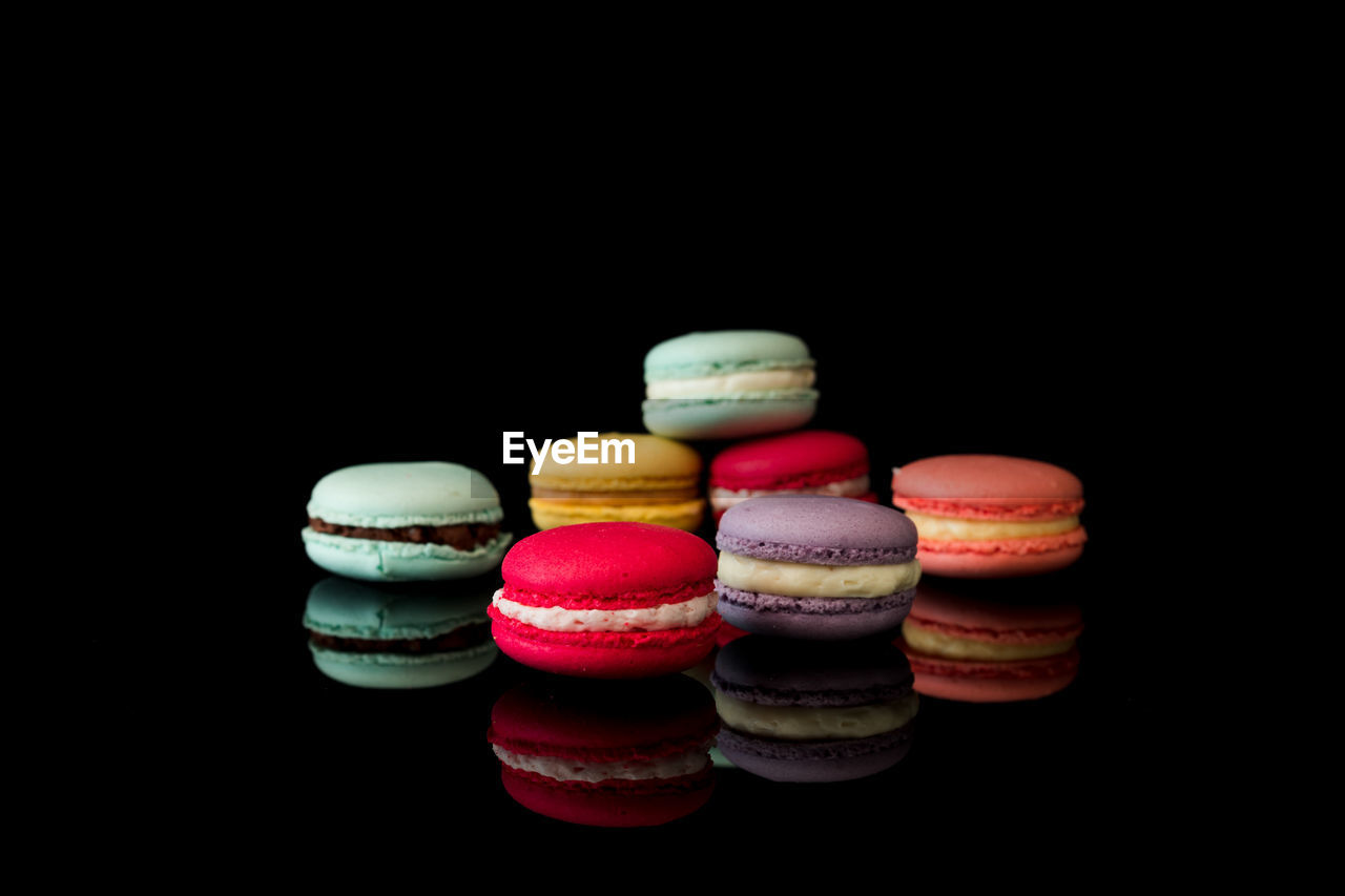 Close-up of multi colored macaroons on table against black background