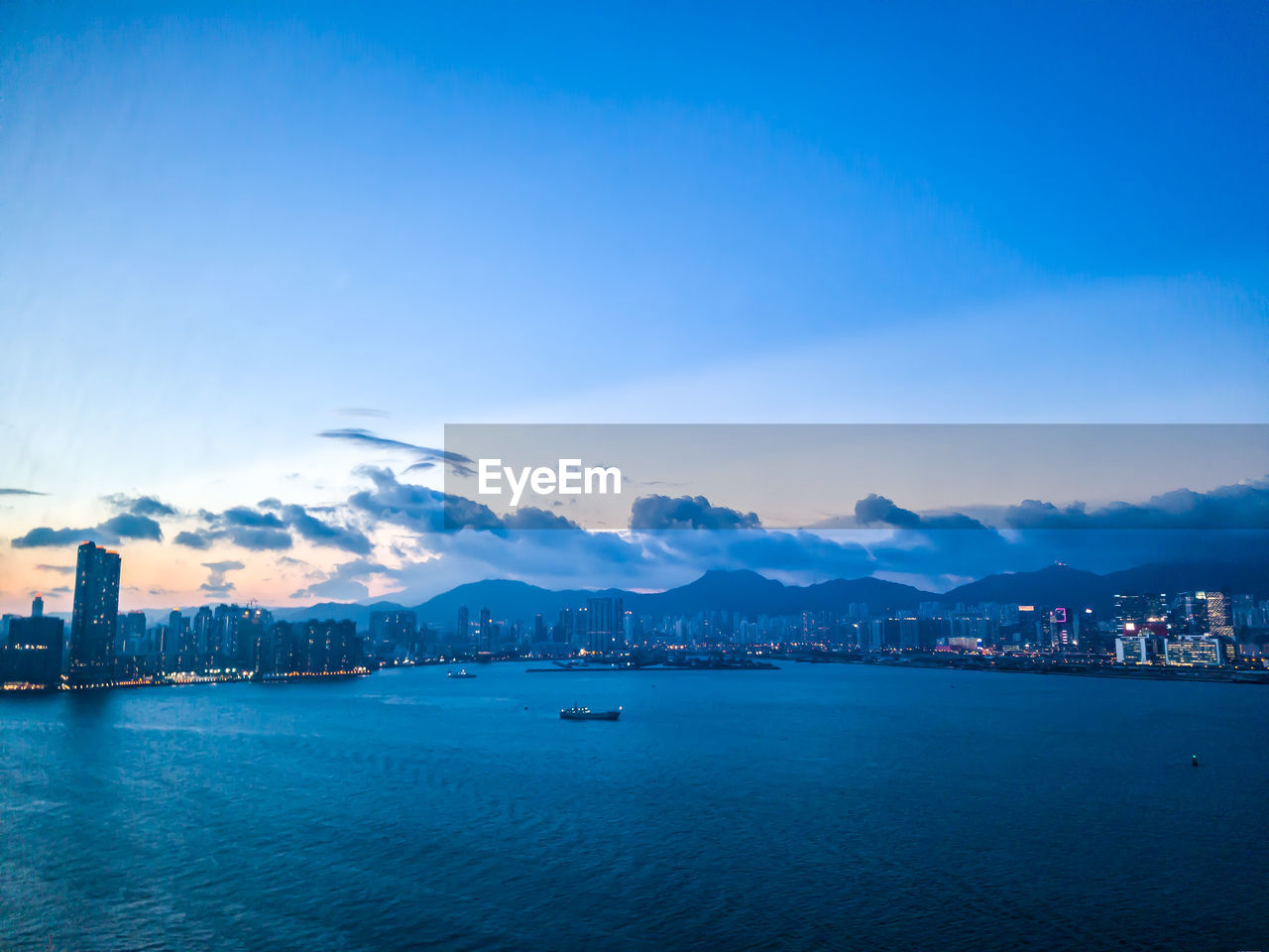 Scenic view of sea by city against blue sky