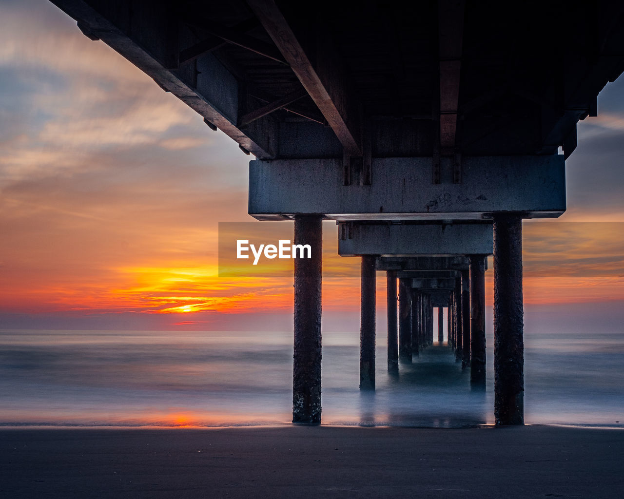 PIER OVER SEA AGAINST ORANGE SKY