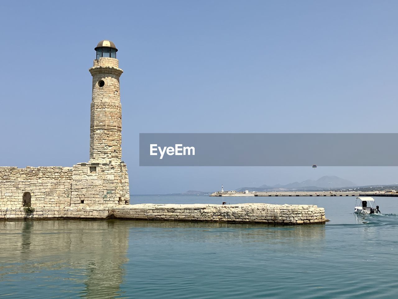 lighthouse by sea against clear blue sky