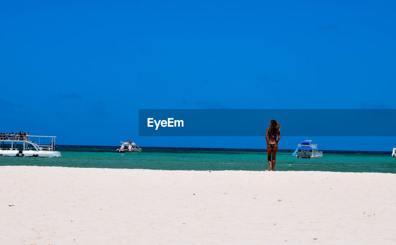 PEOPLE AT BEACH AGAINST CLEAR SKY