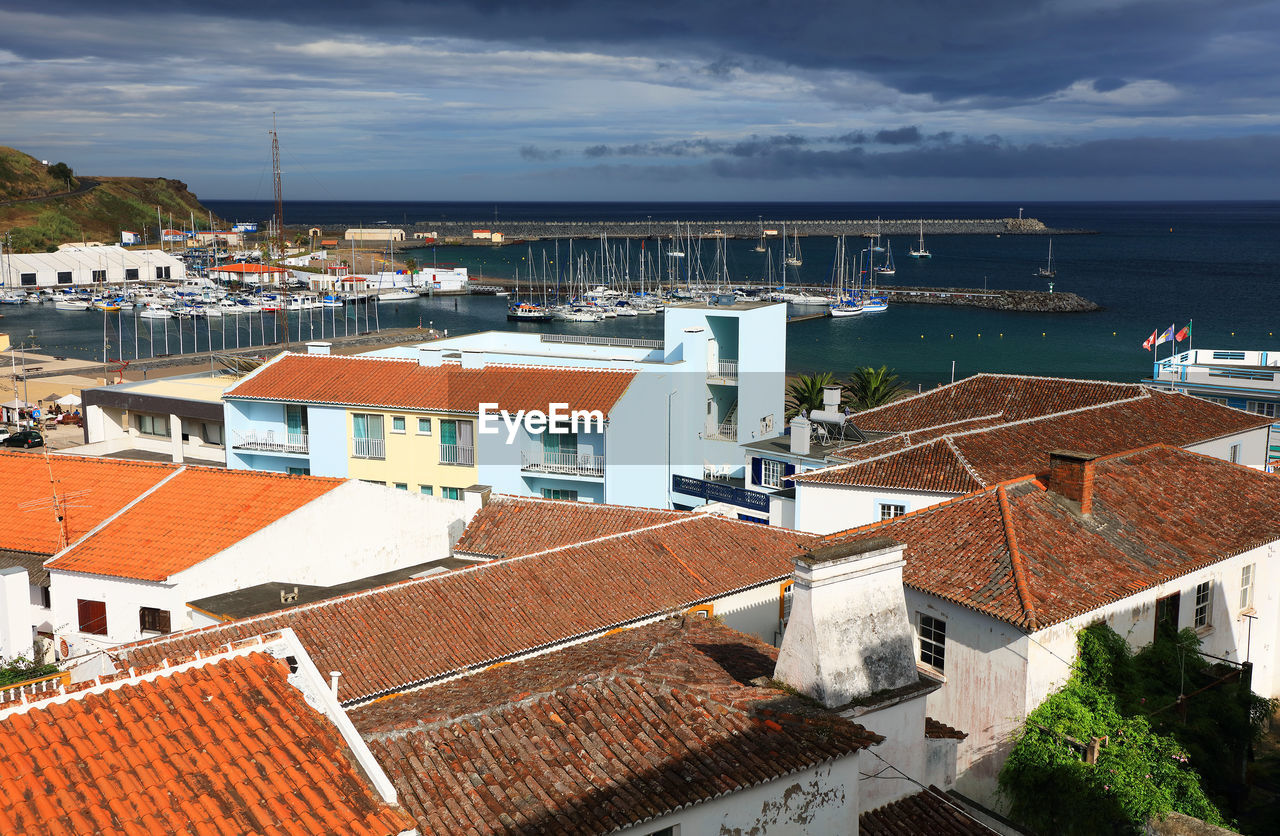 High angle view of houses by sea against sky