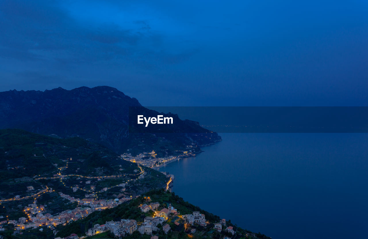 High angle view of sea by mountains against sky